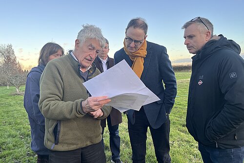 Ian and others in a field looking at some documents