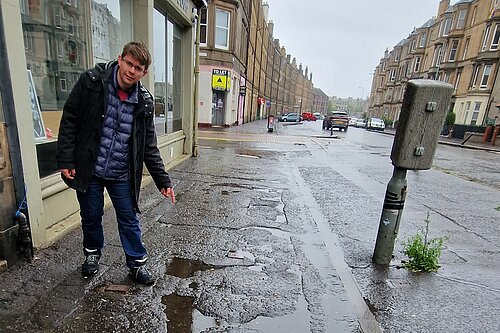 Jack pointing at broken pavements on Easter Road