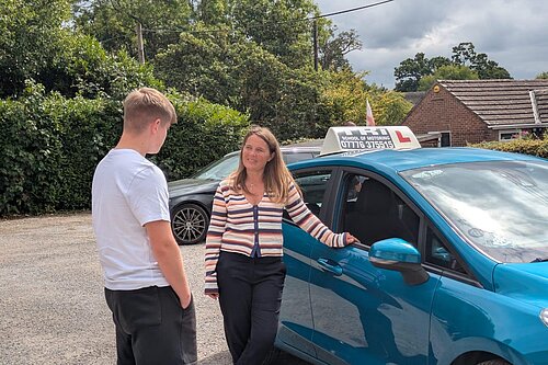 Vikki speaks to a learner driver in front of a car