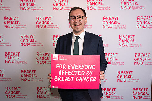 Tom Gordon MP holding a Breast Cancer support sign