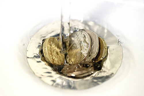 Pound coins going into a drain.