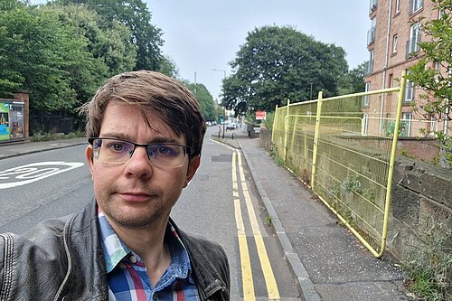Jack standing in front of yellow fencing and a narrow pavement
