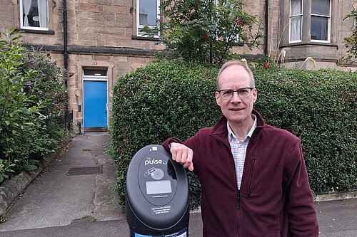 Councillor Neil Ross standing next to an EV charger
